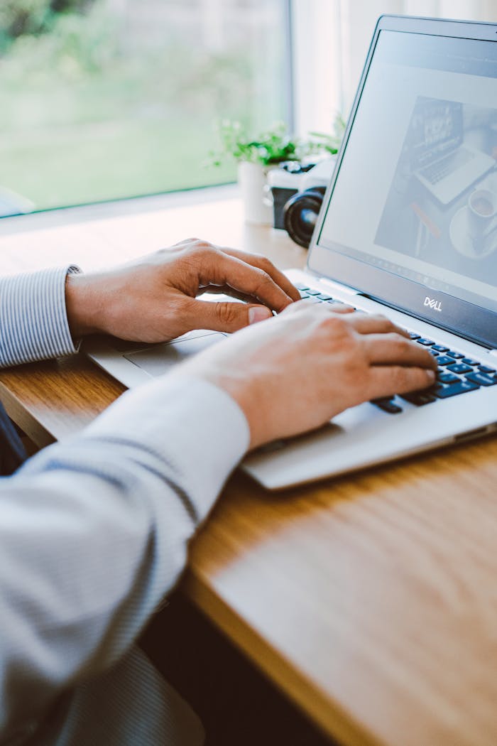 A man working on a laptop in a modern office setting.